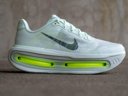 Der Nike Vomero Premium ist das neue Komfortmodell für die Straße von Nike. Mit einer Bauhöhe von rund 55 Millimetern richtet sich der Schuh an Läuferinnen und Läufer, die für ihre Alltagseinheiten sehr viel Dämpfung suchen. Im Vergleich zu klassischen Daily-Trainern verfügt der Vomero Premium über mehr Volumen in der Mittelsohle und sorgt für einen spürbar weicheren Auftritt. Er ist vor allem für umfangreiche Trainingswochen, lange Dauerläufe und Einheiten, bei denen Entlastung im Vordergrund steht, gedacht. Nachdem Nike in diesem Jahr bereits den Vomero 18 und den Vomero Plus vorgestellt hat, ergänzt der Vomero Premium die Reihe nach oben in Richtung maximaler Dämpfung. Optisch sorgt vor allem die üppige Bauhöhe für Diskussionen, da der Schuh deutlich höher aufgebaut ist als die klassischen Vomero-Modelle. Der Vomero Premium lässt sich als Supertrainer mit Fokus auf Komfort einordnen, nicht als Tempomodell. In der Mittelsohle kommt eine durchgehende ZoomX-Mischung zum Einsatz, die um zwei Air-Zoom-Elemente unter Ferse und Vorfuß ergänzt wird. Diese Air-Zoom-Kissen stammen nicht aus den bekannten Straßenracern wie dem Alphafly, sondern orientieren sich eher an der Konstruktion des Spikes Nike Maxfly 2 mit flacherem Aufbau. Das Obermaterial setzt auf leichtes Mesh mit deutlich sichtbarer Polsterung im Fersen- und Zungenbereich. Das Gewicht liegt bei rund 350 Gramm in der Mustergröße, der offizielle Preis bei 230 Euro. Upper und Passform Die Basis des Uppers bildet ein Engineered Mesh, das in mehrere Lagen unterteilt ist. Ein dünner Innenschuh zieht sich über den Zehenbereich und geht in die Zunge über. Darüber liegt eine zweite, ebenfalls dünne Schicht mit punktuell eingesetzten Verstärkungen. So bleibt der Vorfußbereich flexibel, schmiegt sich gut an den Fuß an und wirkt trotz der zusätzlichen Lagen nicht steif. Zunge und Ferse sind deutlich gepolstert und sorgen für einen hohen Tragekomfort. Das Material in der Fersenpartie ist weich genug, um auch bei längeren Einheiten nicht zu reiben, und gleichzeitig stabil genug, um den Fuß in der hohen Mittelsohle zu führen. Die Schnürung funktioniert unauffällig gut und der Schuh lässt sich gleichmäßig an den Fuß anpassen. Ich würde die Passform als mittelbreit einstufen, vergleichbar mit dem Nike Vomero Plus. Im Vorfußbereich steht für die meisten Fußformen ausreichend Platz zur Verfügung, ohne dass der Schuh sehr weit ausfällt. Im Mittelfuß vermittelt das Obermaterial einen soliden Halt, was bei der Bauhöhe wichtig ist, um nicht im Schuh zu „kippen“. Insgesamt bietet der Vomero Premium eine komfortable, aber kontrollierte Passform für normal breite Füße. Mittelsohle und Außensohle Die Mittelsohle ist das zentrale Element des Vomero Premium. Nike setzt hier auf eine ZoomX-Mischung, die sich von den sehr leichten, reinen PEBA-Schaumvarianten der Performance-Modelle unterscheidet. Der Schaum wirkt auf den ersten Blick etwas dichter und alltagstauglicher, bietet aber weiterhin ein spürbar federndes Verhalten. Das Ziel ist eine Kombination aus weichem Auftritt und längerer Haltbarkeit. Unter der Ferse und im Vorfuß sitzt jeweils ein Air-Zoom-Kissen. Diese sind flacher aufgebaut als bei Modellen wie dem Alphafly, bieten aber messbar mehr Rückfederung. Sie unterstützen die Dämpfung und sorgen für ein definiertes Trampolin-Gefühl beim Abdruck, ohne den Schuh in Richtung reiner Racer zu verändern. Von unten sind zwei Bereiche der Mittelsohle offen gelegt. Das spart Gewicht und setzt einen optischen Akzent. Laut Nike sind die Air-Zoom-Kissen ausreichend robust, um auch den Kontakt mit spitzen Steinen auszuhalten. Mit einer Fersenhöhe von rund 55,5 Millimetern ist der Vomero Premium aktuell der höchste Straßenschuh im Nike-Sortiment, die Sprengung liegt mit etwa 10 Millimetern im typischen Bereich. Die Basis ist im Vorfuß und in der Ferse klar verbreitert, was die Stabilität unterstützt. Eine externe Fersenkappe am unteren Fersenrand hilft zusätzlich, den Fuß zentriert zu halten. Die Außensohle kommt im bekannten Waffeldesign von Nike. Der Grip ist im Alltag zuverlässig, die Gummimischung wirkt haltbar und ist somit ideal für den Einsatz als Trainingsschuh. Laufgefühl Bei Schuhen dieser Bauhöhe ist die Erwartung beim ersten Laufen oft ein sehr schwammiges, unpräzises Laufgefühl. Im Fall des Vomero Premium fällt jedoch die für einen derart hohen Schuh bemerkenswert gute Stabilität positiv auf. Die Kombination aus breiter Basis, Air-Zoom-Kissen und strukturierender Fersenkappe sorgt für eine überraschend ruhige Position des Fußes. Man sinkt spürbar, aber nicht unkontrolliert ein, und das Obermaterial trägt zu einem sicheren Sitz bei. Der Komfort ist deutlich ausgeprägt. Die Polsterung im Obermaterial, die ZoomX-Mischung und die Air-Zoom-Elemente sorgen zusammen für einen weichen, aber nicht völlig entkoppelten Auftritt. Durch den ausgeprägten Rocker in der Mittelsohle rollt der Schuh sehr geschmeidig ab. Egal, ob man eher auf der Ferse, im Mittelfuß oder etwas weiter vorne landet, der Übergang in den Abdruck bleibt gleichmäßig. Das Gewicht ist auf dem Papier hoch, fällt beim Laufen aber weniger stark auf als erwartet. Der Vomero Premium gehört zwar nicht zu den leichten Trainern, wirkt im Lauf aber nicht träge. Es gibt Modelle, die nominell leichter sind, sich aber weniger stimmig anfühlen. Sobald das Tempo jedoch deutlich über den moderaten Bereich hinausgeht, stößt der Schuh an seine Grenzen. Aufgrund seiner hohen Bauweise, seines Gewichts und seiner eher komfortorientierten Abstimmung ist er nicht für Tempoeinheiten geeignet. Er ist ideal für ruhige Dauerläufe, längere Einheiten in umfangreichen Trainingswochen und Läufe, bei denen es in erster Linie um Entlastung geht. In diesen Szenarien läuft es sich mit dem Vomero Premium sehr angenehm und der Bewegungsapparat wird spürbar entlastet. Fazit: Der Nike Vomero Premium ist ein Spezialschuh für Läuferinnen und Läufer, die im Alltagstraining viel Dämpfung und hohen Komfort suchen. Er eignet sich insbesondere für lange, ruhige Einheiten, Regenerationsläufe und Trainingsphasen mit hohem Wochenumfang, in denen der Fokus eher auf Schonung als auf Geschwindigkeit liegt. Seine Stärken liegen im weichen und gleichzeitig erstaunlich stabilen Laufgefühl, dem hohen Tragekomfort im Obermaterial und der spürbar federnden Kombination aus ZoomX und Air Zoom. Schwächen zeigt der Schuh bei höherem Tempo. Wer häufig Intervalle, Tempodauerläufe oder Wettkämpfe auf der Straße absolviert, für den sind andere Modelle wie der Megablast oder der Superblast von Asics besser geeignet. Die hohe Bauhöhe und das Gewicht sind zudem Faktoren, die nicht für jede Läuferin und jeden Läufer intuitiv funktionieren. Mit einem Preis von 230 Euro ist der Vomero Premium eher ein Zusatzschuh im Sortiment als die einzige Trainingsoption. Wer bereit ist, diesen Betrag für ein sehr komfortorientiertes Modell zu investieren und bewusst nach einem stark gedämpften Supertrainer sucht, erhält mit dem Vomero Premium einen interessanten Schuh für entspannte und lange Distanzen. Wer ein kleineres Budget hat oder eine etwas konventionellere Abstimmung bevorzugt, ist mit dem Vomero Plus in vielen Fällen gut bedient.