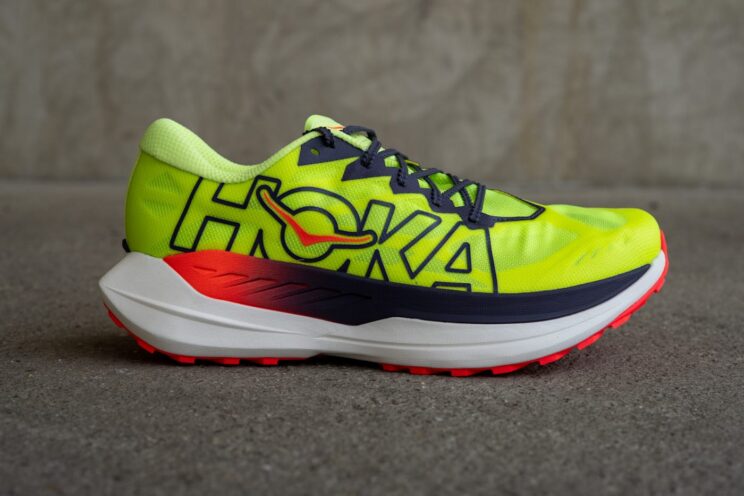 Hoka Rocket X Trail Laufschuh auf Gravel, gelb mit schwarzen Akzenten.
